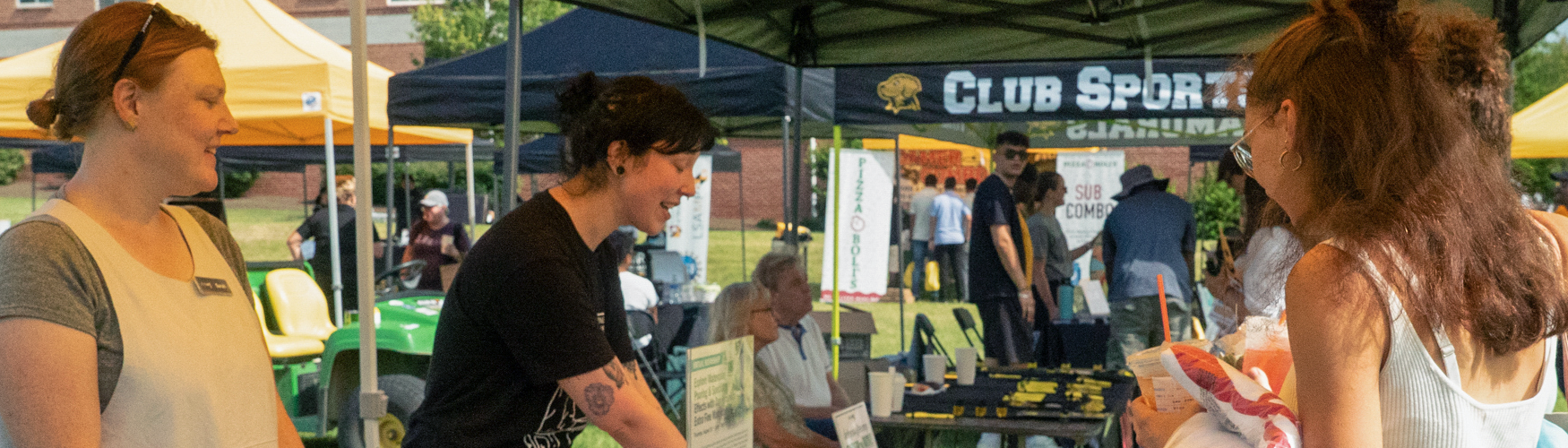 Two staff and a student discussing resources over a table at Retriever Fest